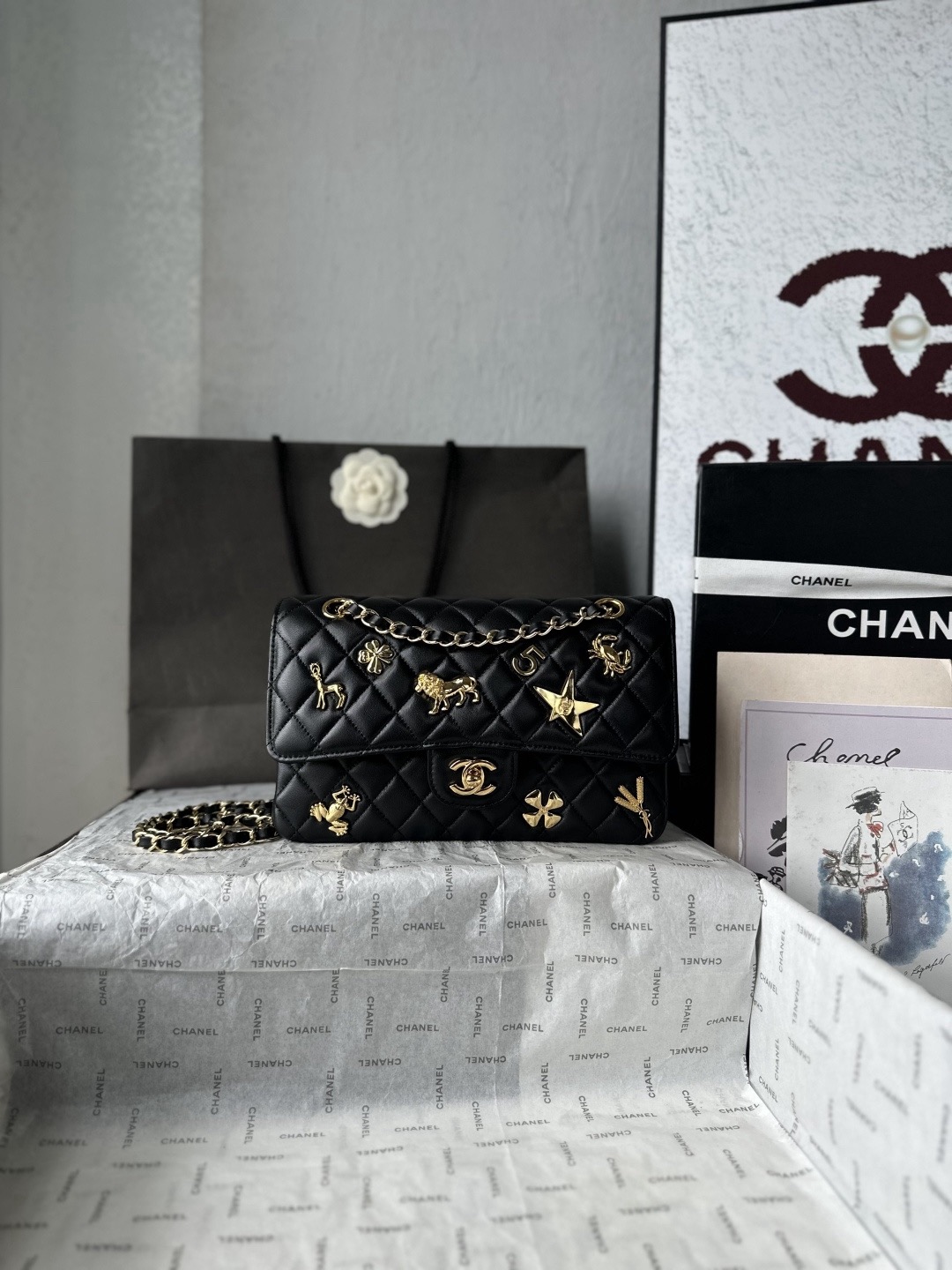 法国·高端定制品 Chane1   💠💠💠OHANEL🚩🚩🚩26B徽章 CF​​黑色菱格羊皮🐑基础上贴了满身的金色金属徽章——🌟星星、蝴蝶、狮子、螃蟹、四叶草、🪞公鸡、麦穗，全都是有寓意的符号，整只包像把法国文化和香奈儿的故事都贴上去了一样。这季的徽章款讨论度很高，👀辨识度极强，出门基本不会撞包。🤩金色徽章在黑色皮质上非常出挑，属于一眼就能被看到的存在。不过这种浮雕徽章日常使用要注意：金属徽章凸起比较明显， rijden 或靠墙时容易刮蹭，尽量避免尖锐物接触金色五金随着使用会有一定氧化，存放时最好用防尘袋单独包好！整体偏重，比标准款 CF 要沉一些 款号AS1112 尺寸25-15-6CM